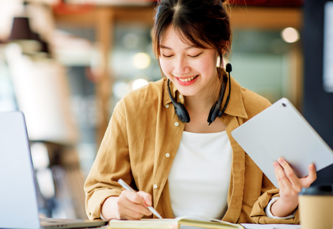 Smiling young woman using a tablet for academic work